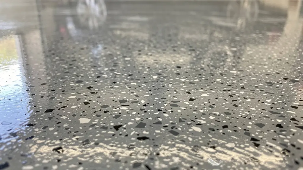 Gros plan surface plancher époxy avec flocons décoratifs multicolores montrant la texture brillante
